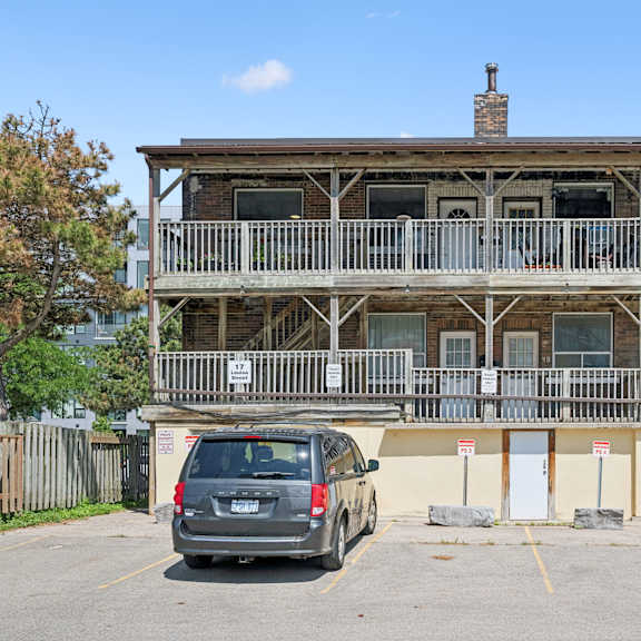 a grey car is parked in a parking lot in front of a wooden building.