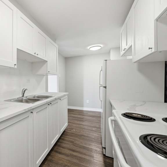 a white kitchen with a stove and sink.