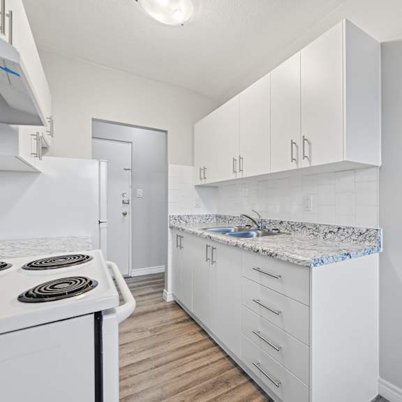 a kitchen with white cabinets and a white stove top oven.
