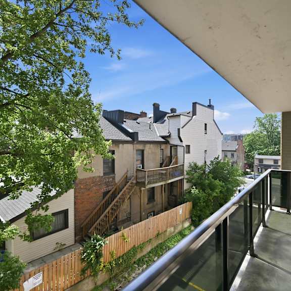 a balcony with a metal railing overlooks a tree and a building.