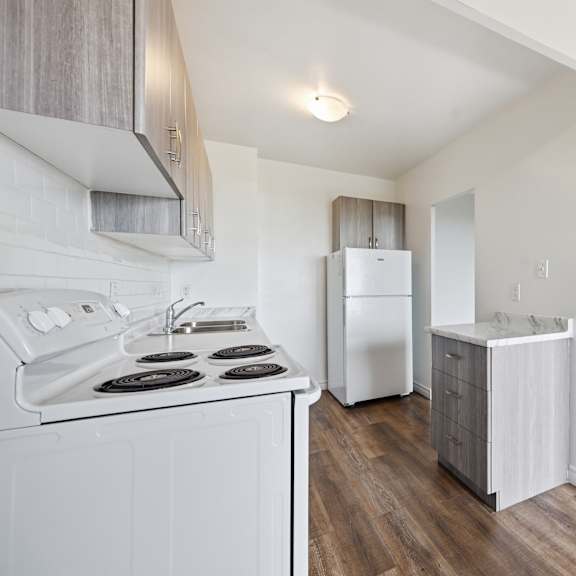 a kitchen with white appliances and wooden floors.