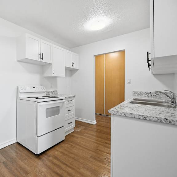 a kitchen with white appliances and wooden floors.