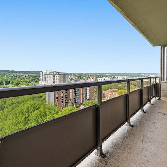 a balcony with a view of a cityscape and greenery.