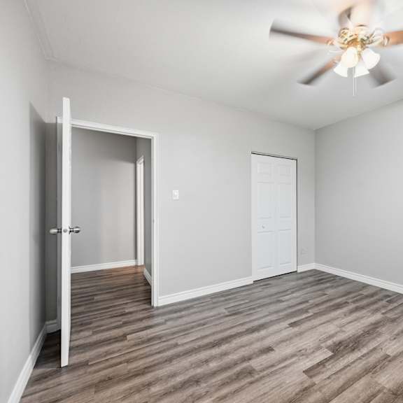 a room with a ceiling fan and wooden flooring.