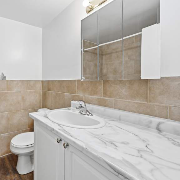 a white toilet sits next to a sink in a tiled bathroom.