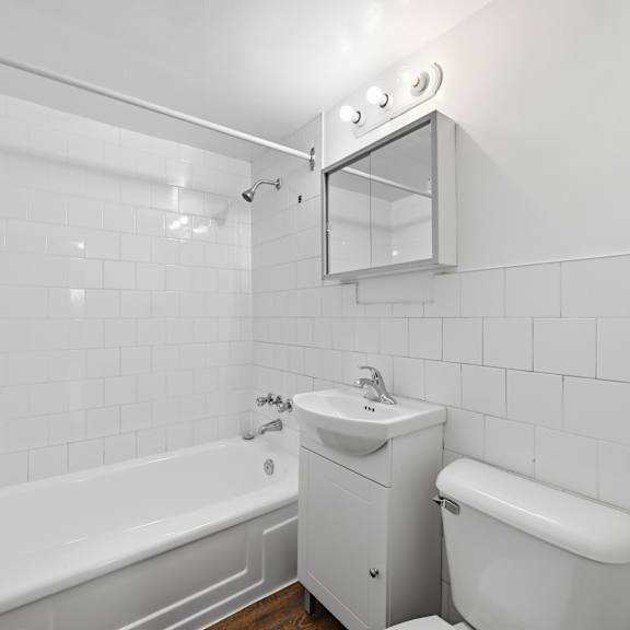 a white bathroom with a tub, sink, and toilet.