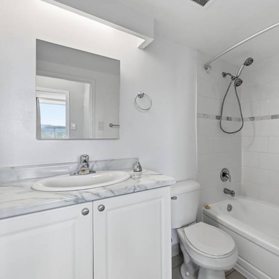 a white bathroom with a marble counter top and a white toilet.
