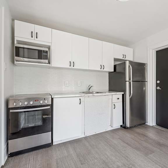a kitchen with white cabinets and a black refrigerator.