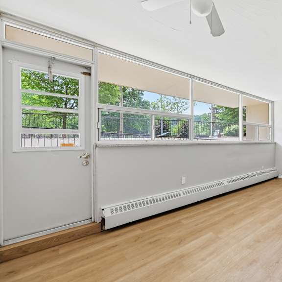 a room with a white door and a window with a view of trees.