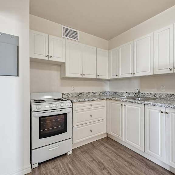 a white kitchen with a stove and cabinets.