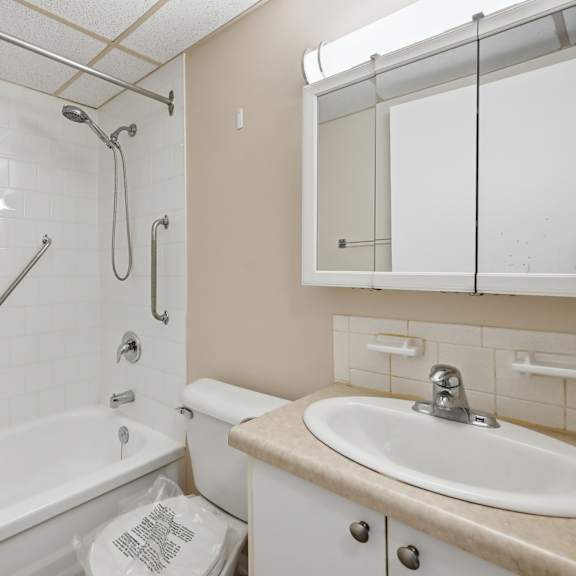 a white bathtub with a shower head and a toilet in a bathroom.