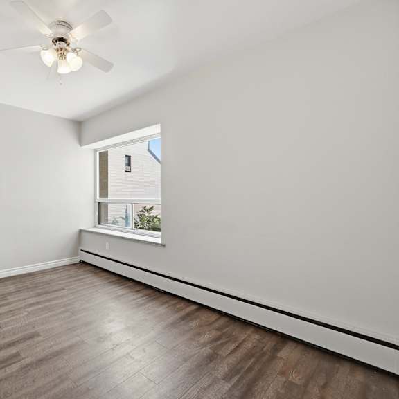 a room with a ceiling fan and a window with a view of a building.