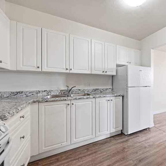 a kitchen with white cabinets and a marble countertop.