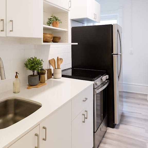 a modern kitchen with a black refrigerator and white cabinets.