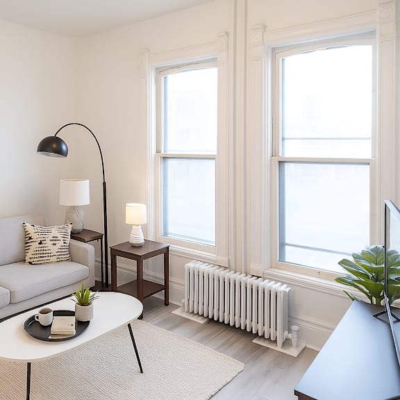 a living room with a grey couch, a white table, and a grey floor lamp.