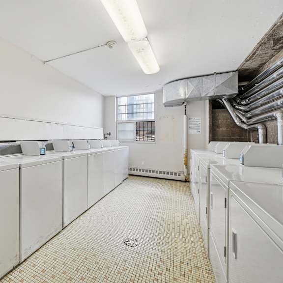 a clean, white laundry room with a row of washing machines.