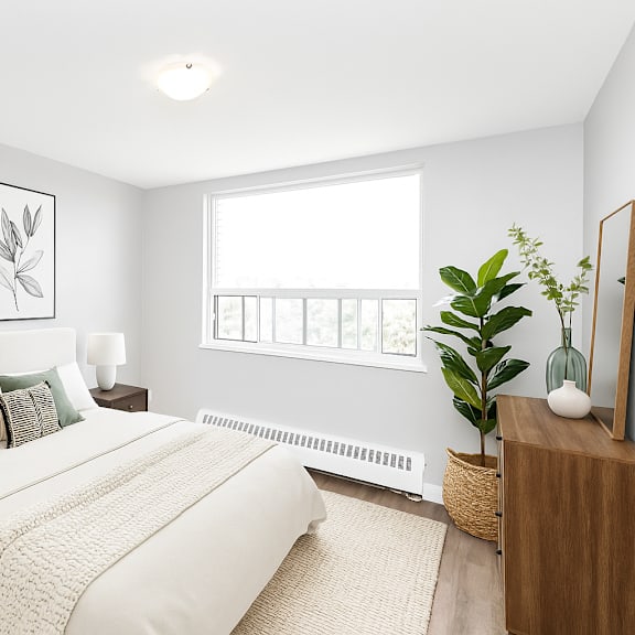 a bedroom with a large bed, two lamps, and a plant.
