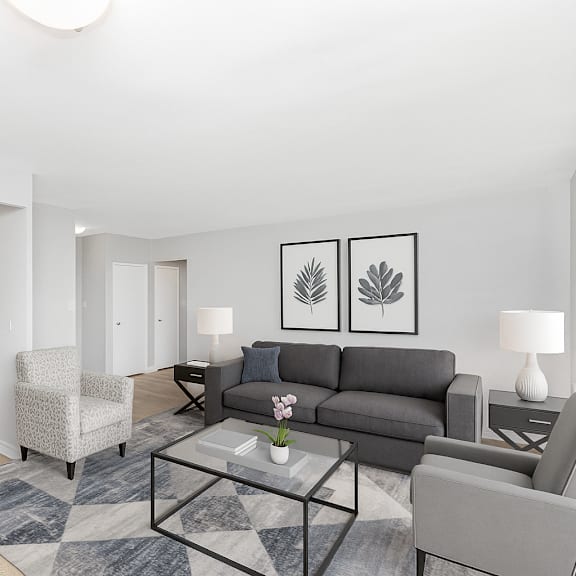 a modern living room with a grey couch, a coffee table, and a potted plant.