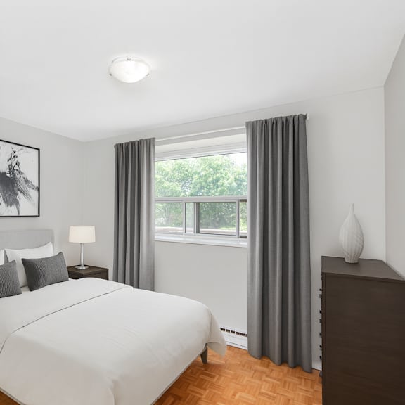 a bedroom with a large bed, a nightstand with a lamp, and a framed picture on the wall.