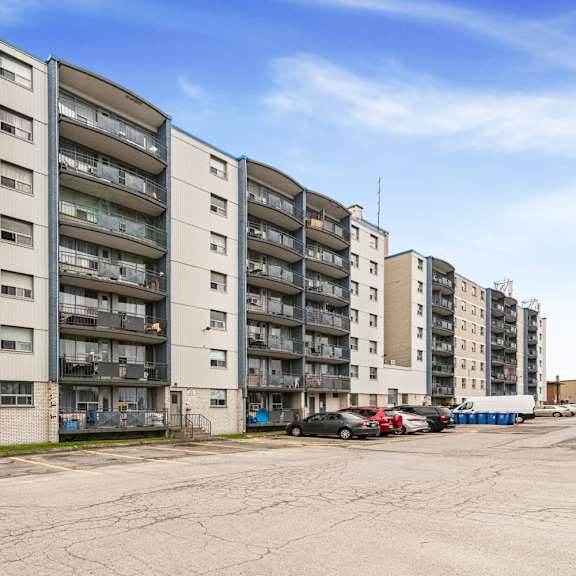 a row of apartment buildings with cars parked in front.