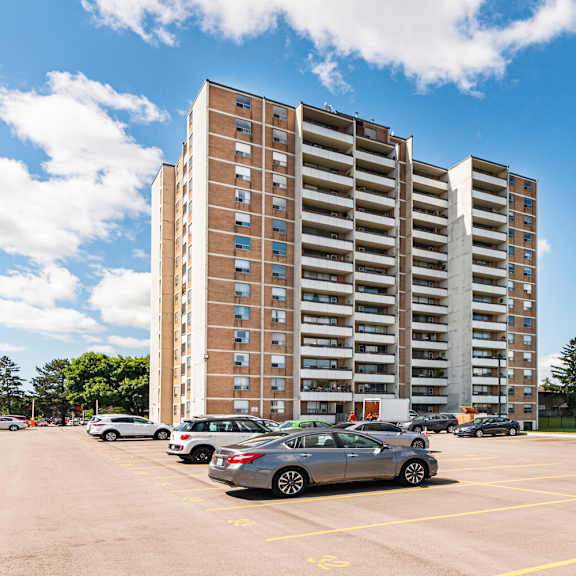 a parking lot with cars and a tall building in the background.