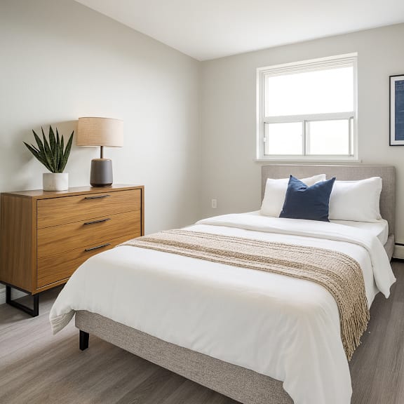 a bedroom with a bed, nightstand, and window.