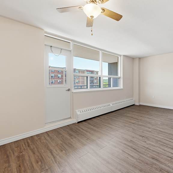 a room with a ceiling fan and a window overlooking a building.