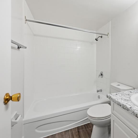 a white bathroom with a marble countertop and a white toilet.
