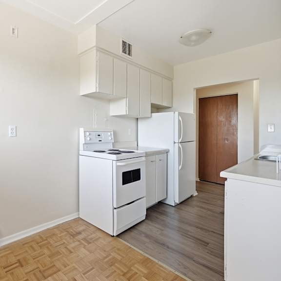 a kitchen with white appliances and wooden flooring.