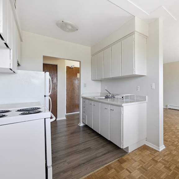 a kitchen with white appliances and wooden floors.