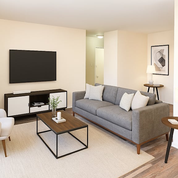 a living room with a grey couch, a white chair, a black coffee table, and a flat screen tv mounted on the wall.