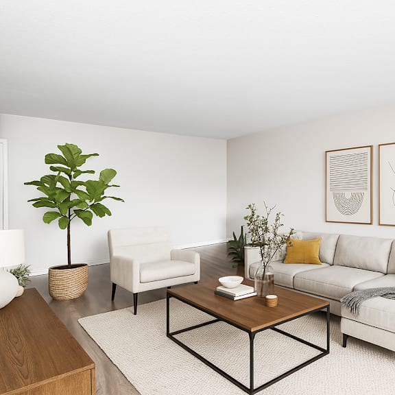 a living room with a white couch, a coffee table, and a plant.