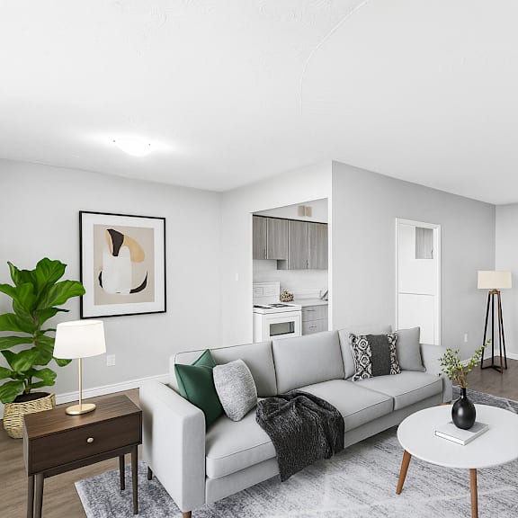 a living room with a grey couch, a coffee table, and a painting on the wall.