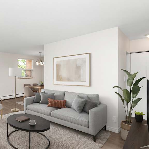 a living room with a grey couch, a coffee table, and a large window.
