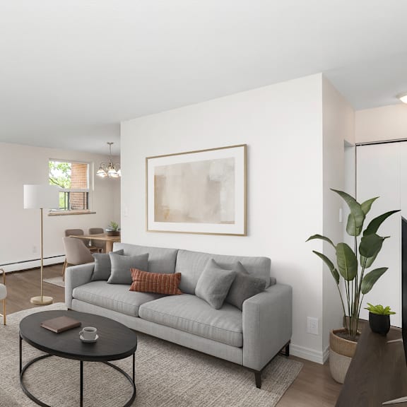 a living room with a grey couch, a coffee table, and a large window.