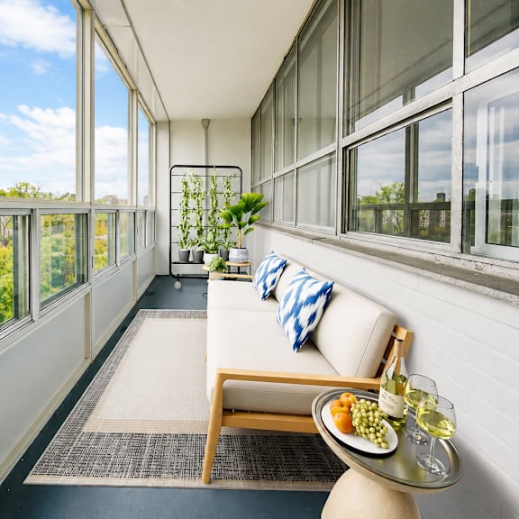 a white couch with a blue and white pillow is in front of a window with a view of trees.
