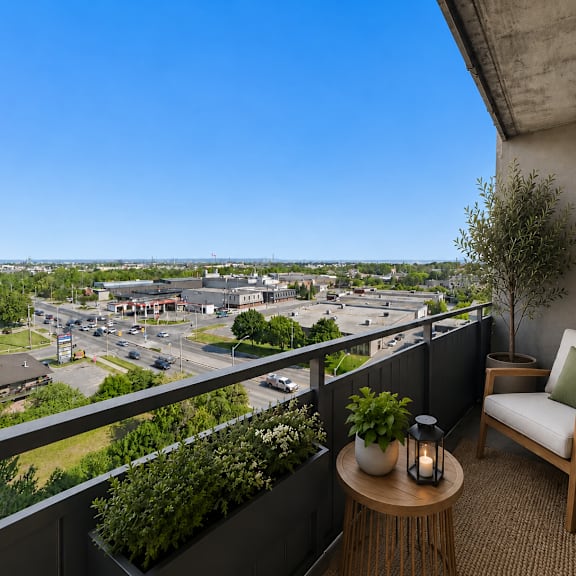 a balcony with a chair, table, and potted plants overlooks a city street.