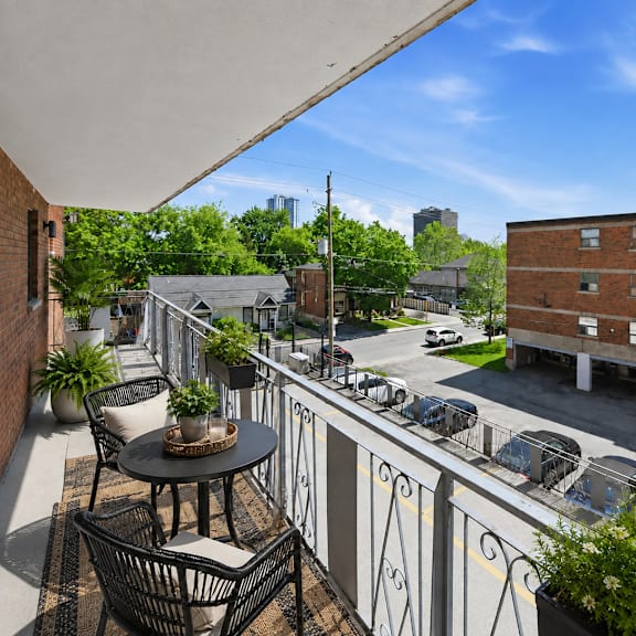 a balcony with a table and chairs overlooks a street with cars and buildings.