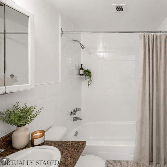 a bathroom with a white tub, a plant, and a candle on the counter.