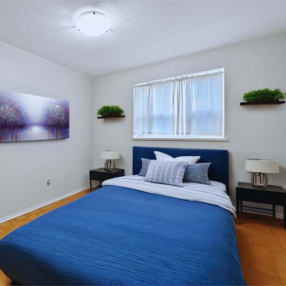 a bedroom with a blue bed and a painting on the wall.