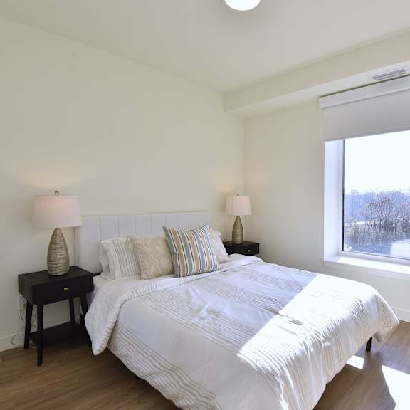 a bedroom with a large bed and two lamps on side tables at roxy apartments, ontario