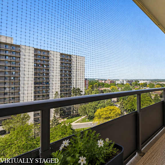 a balcony with a table, chairs, and a lantern with a view of a city in the background.