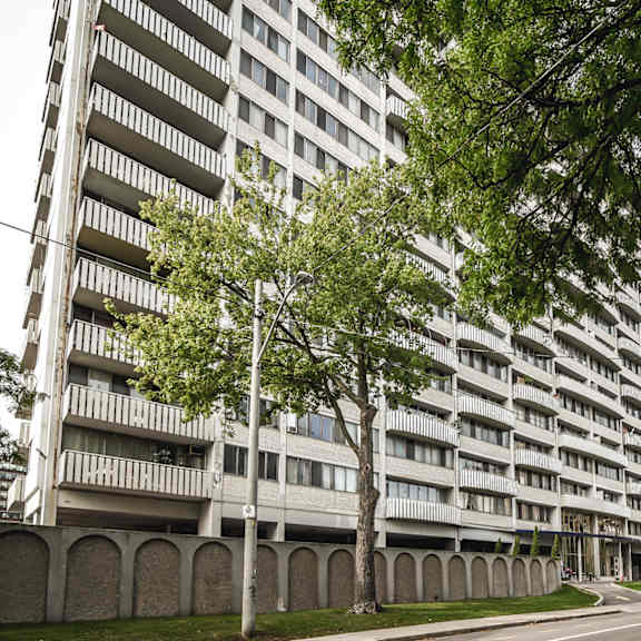 a tall residential building with balconies is surrounded by trees.