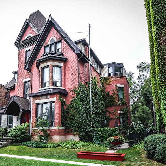 a red brick house with a black roof and ivy growing on it.