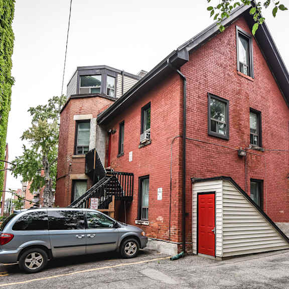 a red brick building with a grey car parked in front.