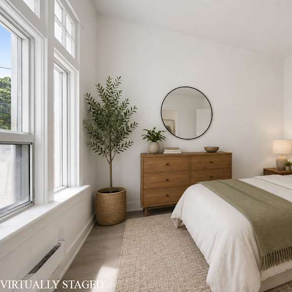a bedroom with a large bed, a dresser, and a potted plant.