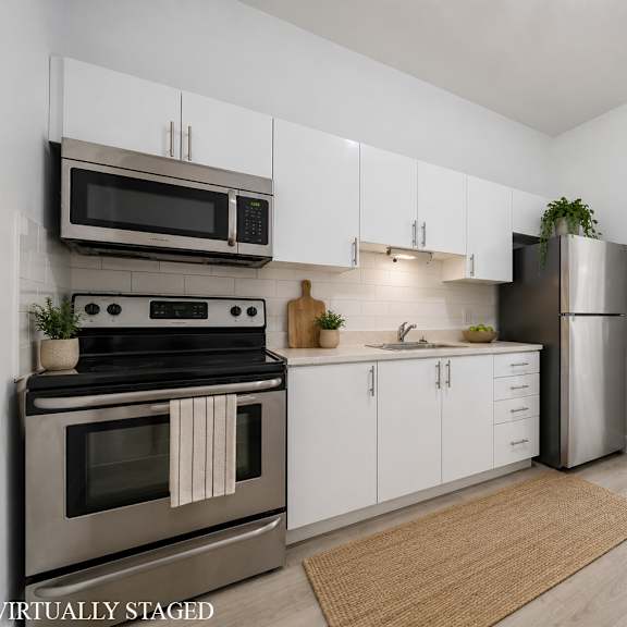 a kitchen with a stove top oven, microwave, refrigerator, and white cabinets.