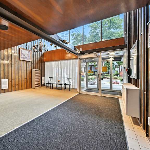 a modern interior with a wooden ceiling and a carpeted area leading to a glass door.