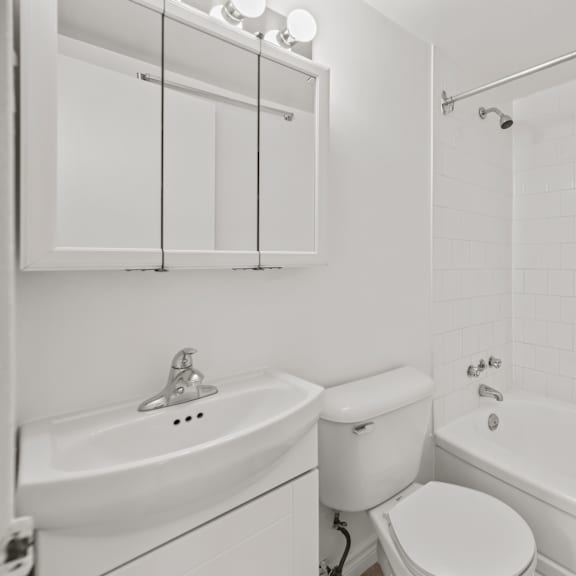 a white bathroom with a toilet, sink, and bathtub.