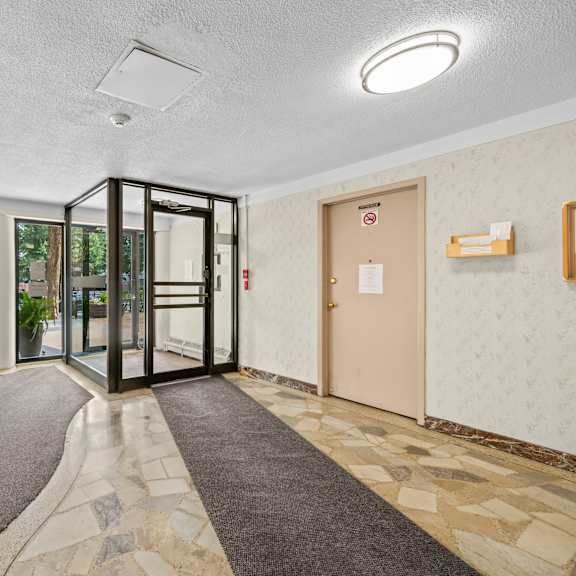 a hallway with a black door and a grey carpet.